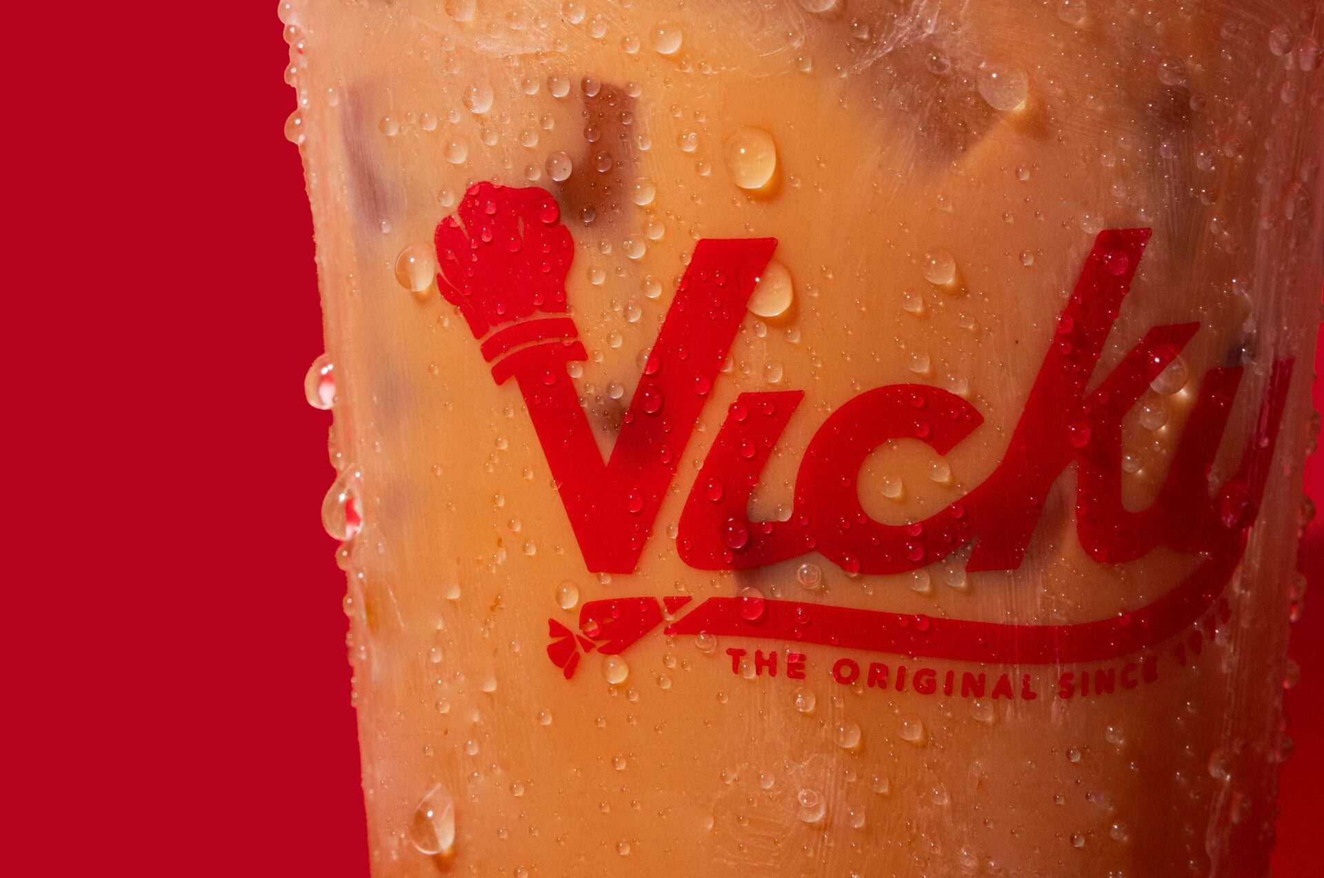 Close-up of an iced coffee in a plastic cup with condensation, featuring the red 'Vicky Bakery – The Original Since
